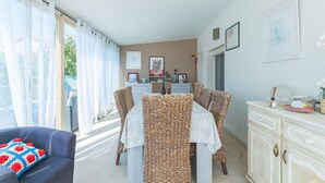 A dining area with a table, chairs, and a cabinet. - Apartment 'Les Cerisiers' with Shared Pool, Shared Terrace and Wi-Fi (Apt)