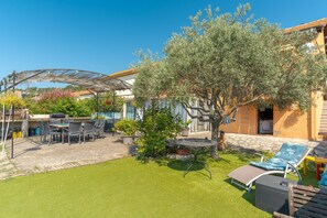 A patio with outdoor furniture, a pergola, and a tree.