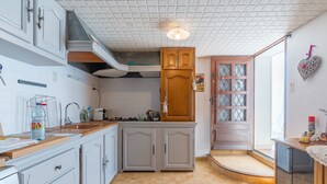 A kitchen with white cabinets, a wooden countertop, a tiled backsplash, and a wooden door with glass panels. - Apartment 'Les Cerisiers' with Shared Pool, Shared Terrace and Wi-Fi (Apt)