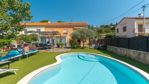 A swimming pool with lounge chairs, a patio area, and a house in the background. - Apartment 'Les Cerisiers' with Shared Pool, Shared Terrace and Wi-Fi (Apt)