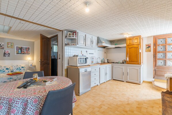 A compact kitchen with white cabinets, a microwave, and a sink. There is a dining area with a table and chairs.