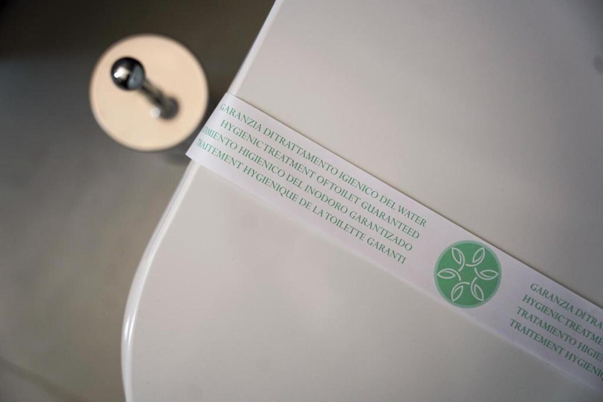 Eine Toilette mit einem Schild, das anzeigt, dass es sich um eine ‚Garanzia Ditrata‘ oder ‚Guaranteed Treatment‘ für erhöhte Hygiene handelt.