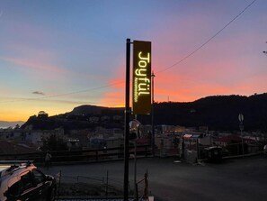 A sign for 'Joyful Accommodation' with a view of a cityscape at sunset.