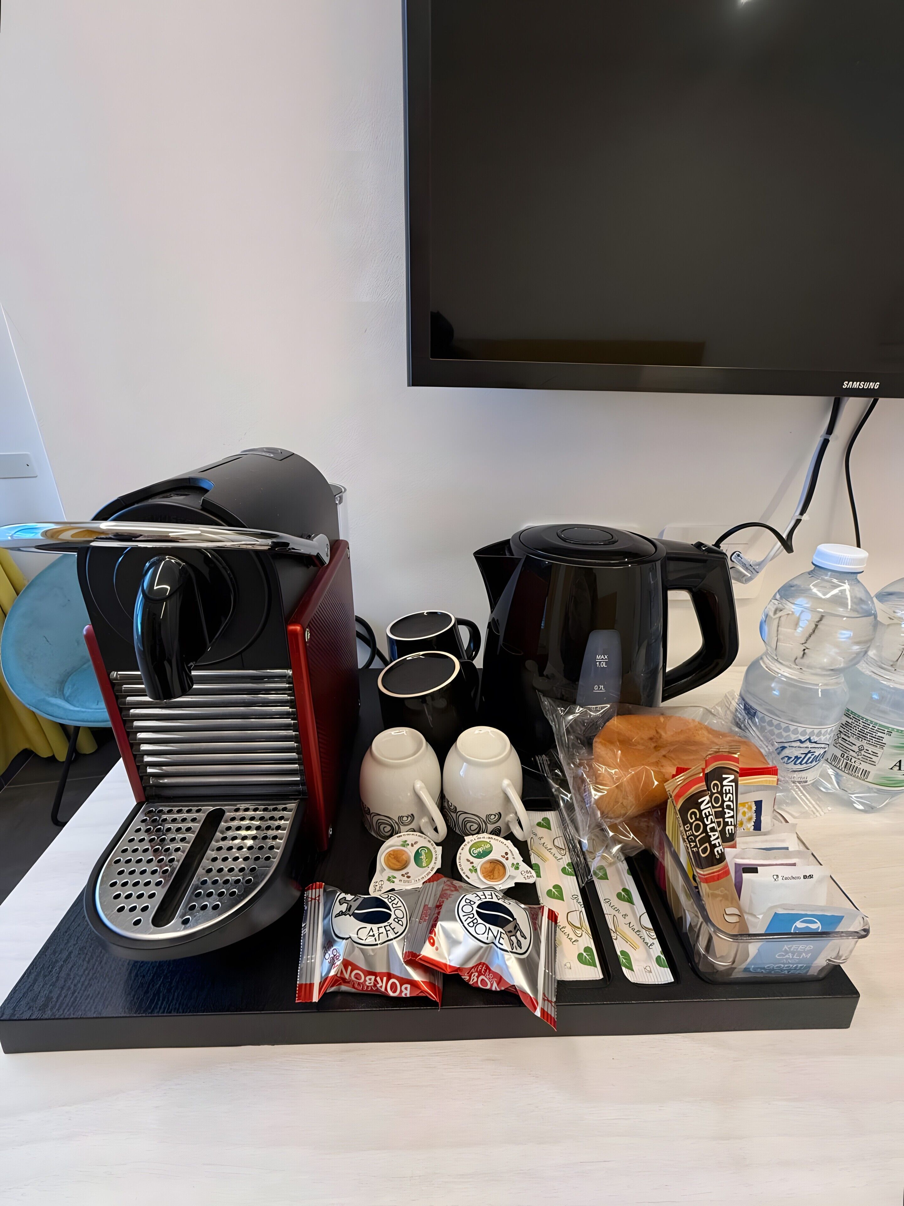 Un angolo caffè con macchina da caffè, tazze, un tostapane e prodotti per la colazione come pane e cialde per caffè.