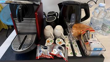 Un angolo caffè con macchina da caffè, tazze, un tostapane e prodotti per la colazione come pane e cialde per caffè.