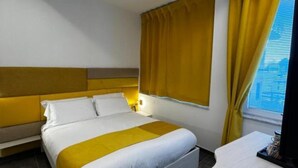 Una habitación de hotel con cama, mesita de noche y escritorio con silla.