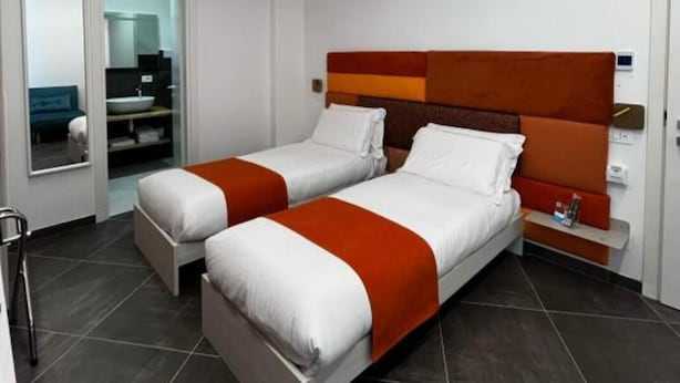 Ein Hotelzimmer mit zwei Betten, einem Badezimmer und einer kleinen Sitzecke.