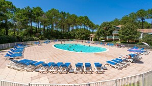 Area piscina con lettini e una piscina circondata da alberi.
