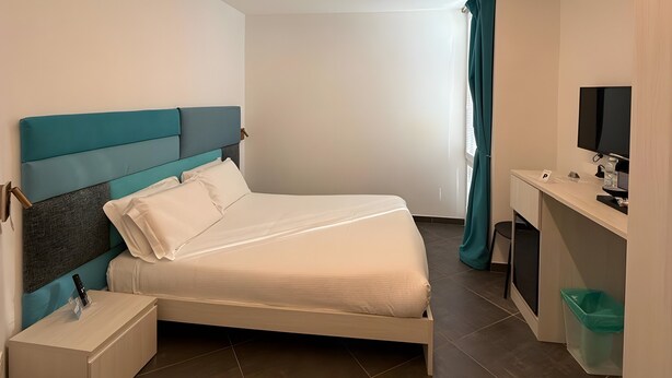 Ein modernes Schlafzimmer mit Bett, Nachttisch, Schreibtisch und Fernseher.