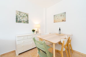 Un coin repas comprenant une table en bois, des chaises, un meuble blanc, une lampe et deux œuvres d’art accrochées au mur.