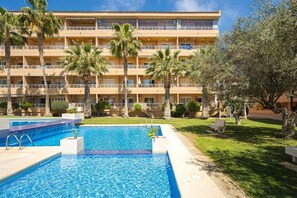 Un hotel con piscina, palmeras y un edificio de varios pisos.