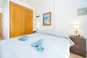 Une chambre d’hôtel avec un lit, une armoire en bois, une table de chevet avec une lampe et un tableau accroché au mur.