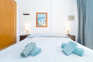 A hotel room with a bed, two bedside tables, a wall-mounted picture, and a door.