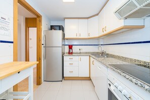 A kitchen with white cabinets, a microwave, a refrigerator, a stove, and a sink.