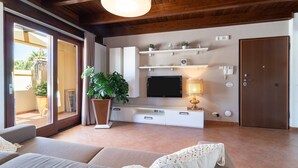 Un soggiorno moderno con divano, televisore e piante.