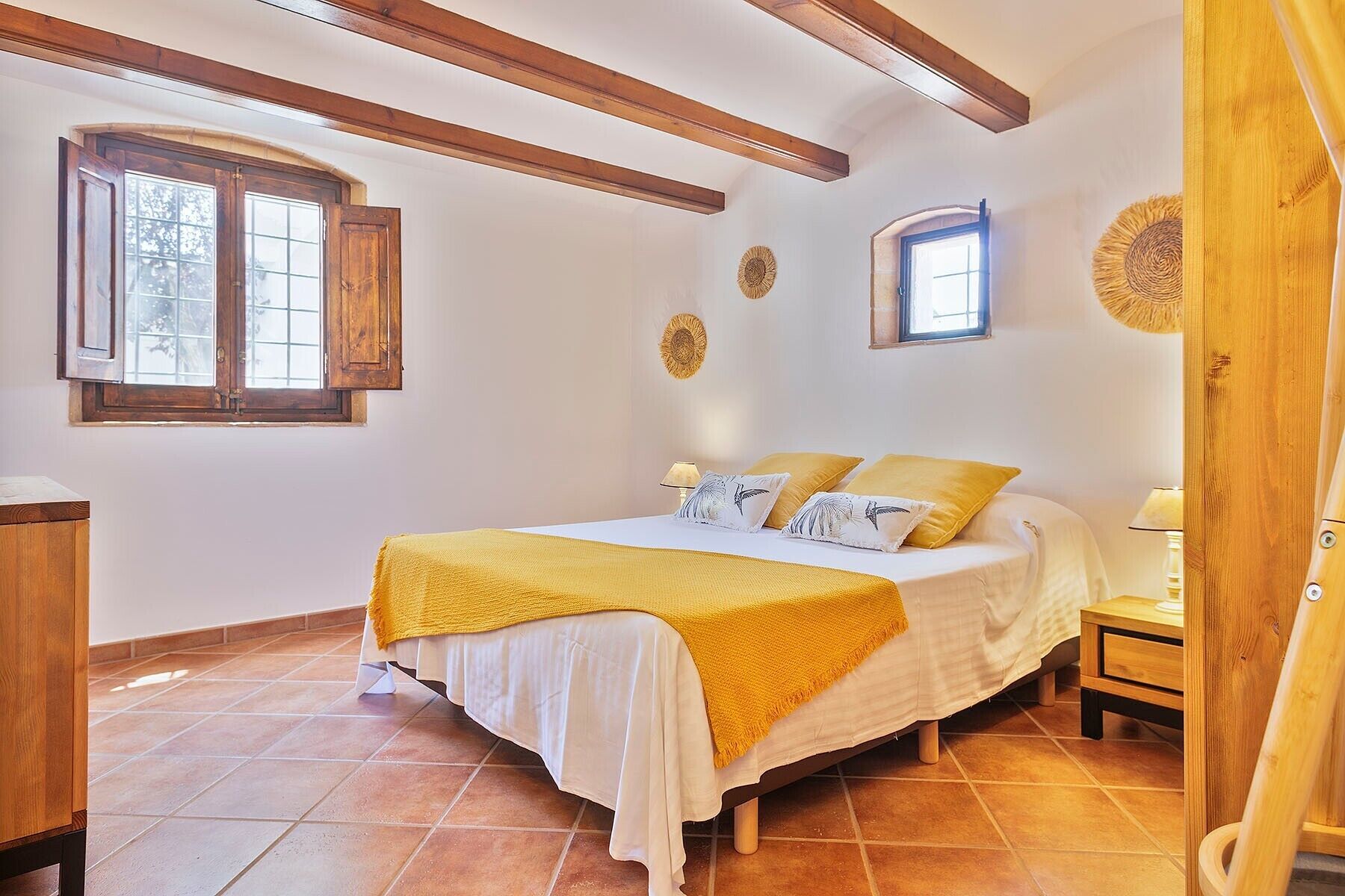 Ein Schlafzimmer mit einem Bett, zwei Nachttischen, einem Fenster und einer Tür.