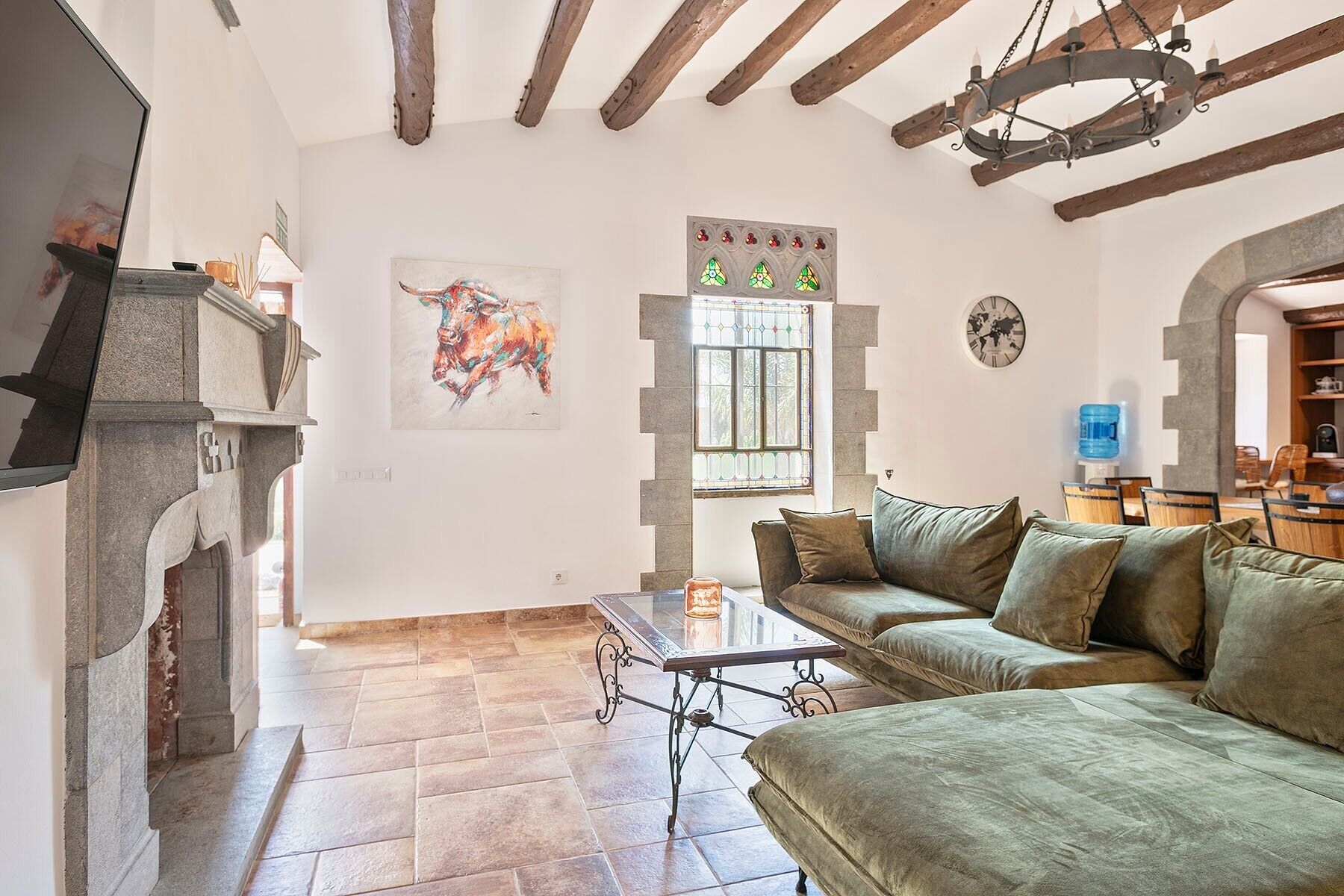 A living room with a stone fireplace, a green sofa, a coffee table, and a painting of a bull.