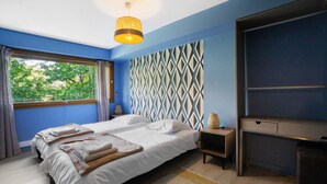 A bedroom with a bed, bedside tables, a desk, and a window with curtains. - Apartment 'Chez Anna' with Mountain View, Wi-Fi and Air Conditioning (Saint-Jean-de-Maurienne)