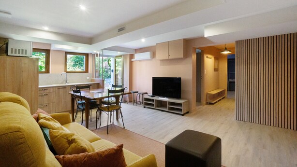 A modern living room with a sofa, TV, and dining area. - Apartment 'Chez Anna' with Mountain View, Wi-Fi and Air Conditioning (Saint-Jean-de-Maurienne)