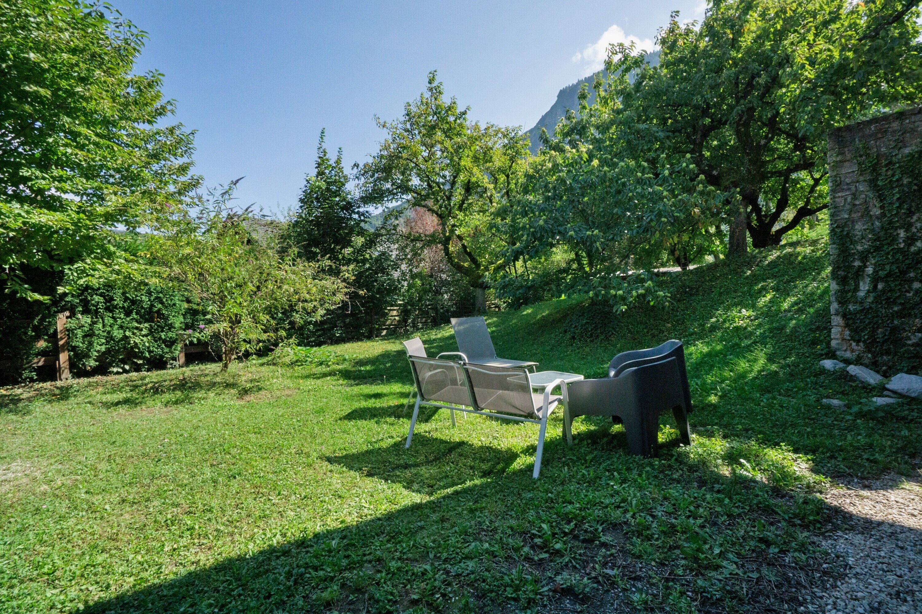 A grassy outdoor area with a seating arrangement and a stone wall.