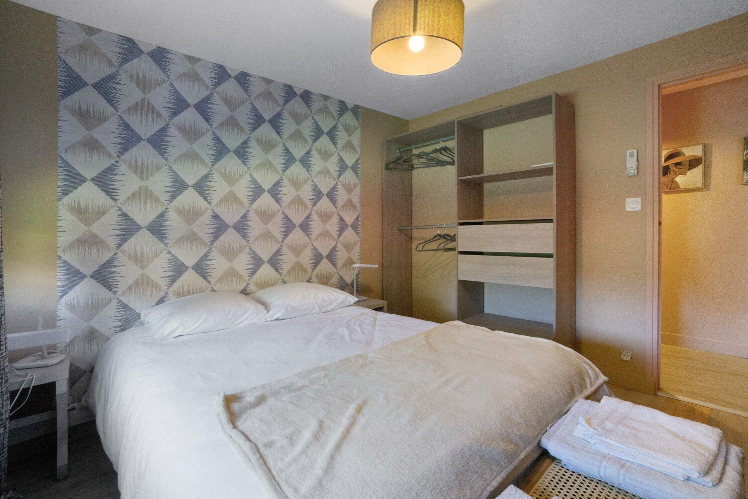 A hotel room with a bed, a bedside table, a wardrobe, and a mirror.