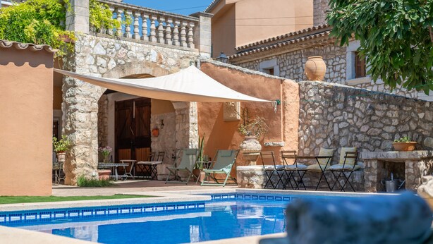 A pool area with a stone wall, outdoor seating, and a covered patio. - Holiday Home 'Ca'n Blanch' with Private Pool, Terrace and Wi-Fi (Biniamar)