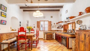 A kitchen with wooden furniture, a dining table, and a window. - Holiday Home 'Ca'n Blanch' with Private Pool, Terrace and Wi-Fi (Biniamar)