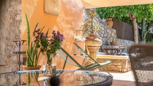 A patio with a glass table, potted plants, and outdoor furniture. - Holiday Home 'Ca'n Blanch' with Private Pool, Terrace and Wi-Fi (Biniamar)