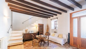 A room with a staircase, a dining table with chairs, a sofa, a wooden cabinet, and a radiator. - Holiday Home 'Ca'n Blanch' with Private Pool, Terrace and Wi-Fi (Biniamar)
