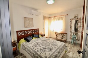 A bedroom with a bed, a dresser, a mirror, and a window with curtains. - Apartment 'Felicidad' with Mountain Views, Wi-Fi and Air Conditioning (Dénia)