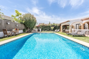 Una piscina con sillas de descanso y una pérgola.
