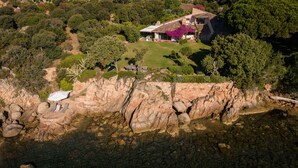An aerial view of a coastal property with a stone retaining wall, a grassy lawn, and a house with a tiled roof. - 
2 471 / 5 000
Villa A Cala d Oro with private beach, garden with sea view, Wi-Fi and AC (Porto-Vecchio)