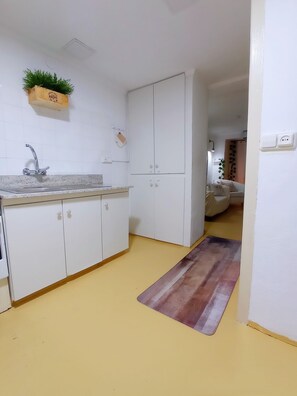 A kitchen with white cabinets, a granite countertop, a sink, and a wooden floor mat.