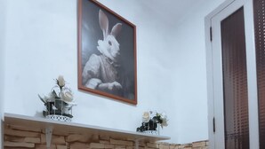Une pièce avec un mur en pierre, un tableau encadré représentant un lapin et une porte avec une fenêtre.