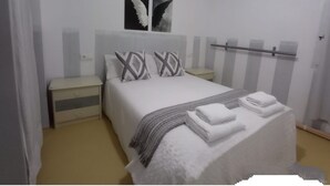 Une chambre à coucher avec un lit, des oreillers, une table de chevet et une commode.