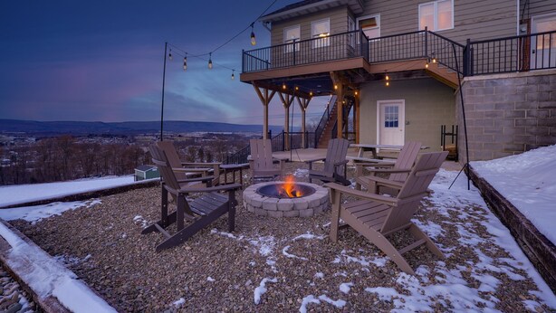 A house with a fire pit, outdoor seating, and a balcony overlooking a snowy landscape. - The View at Stoney Acres |  Pool + Hot Tub + Views (Mifflinburg)