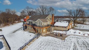 A large house with a covered deck and a garage. - The View at Stoney Acres |  Pool + Hot Tub + Views (Mifflinburg)