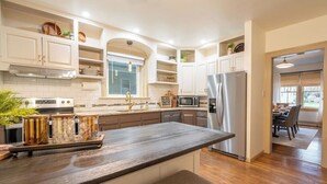 Een moderne keuken met witte kastjes, een roestvrijstalen koelkast en een houten aanrecht.