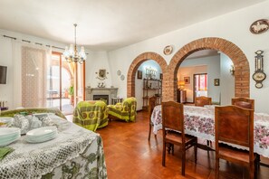 Comedor con una mesa dispuesta para cuatro, chimenea y vista a otra habitación por medio de un arco.