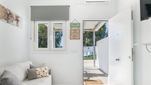 A modern living room with a sofa, a small table, a window, and a door leading outside.