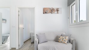 A modern living room with a grey sofa, a small table, and a painting on the wall.