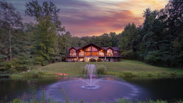 A large lodge with a central water feature and a surrounding forest.