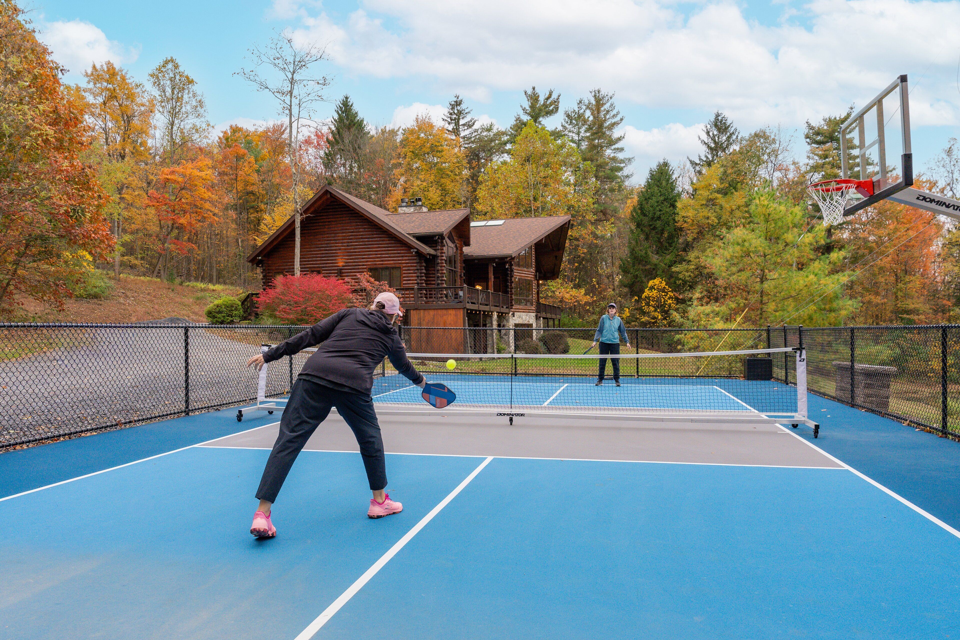 Un campo da tennis all'aperto con una casetta in legno sullo sfondo.