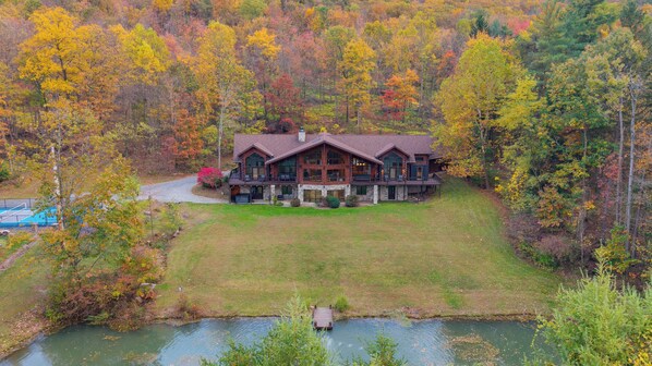 A large log cabin with a deck and a swimming pool.