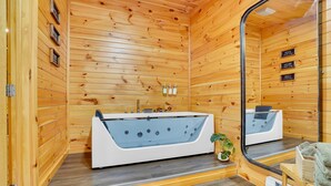 Une cabane en bois avec une grande baignoire, un miroir et une petite plante.