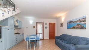 Een compacte leefruimte met een kitchenette, een eethoek en een bank.