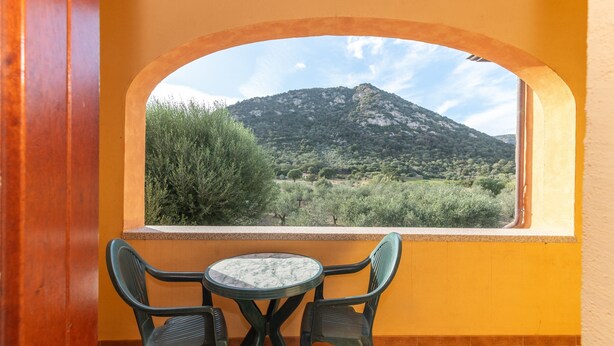 Een balkon met uitzicht op een berg, een tafel en twee stoelen.