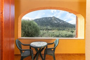 A balcony with a view of a mountain, a table, and two chairs. - Holiday Home 'Casa Vacanza San Teodoro' with Barbecue, AC, and 2 Private Parking Spaces (L'alzoni)