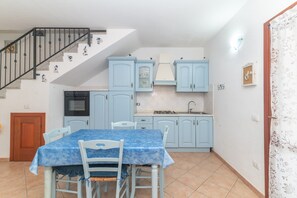 A kitchen with light blue cabinets, a dining table with a blue tablecloth, and a staircase with decorative elements.