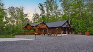 A log cabin with a porch, surrounded by a gravel driveway and forest. - Mountainside Cabin | Pickleball Court, Pavilion + Fire Pit, Near ATV Trails (Allenwood)